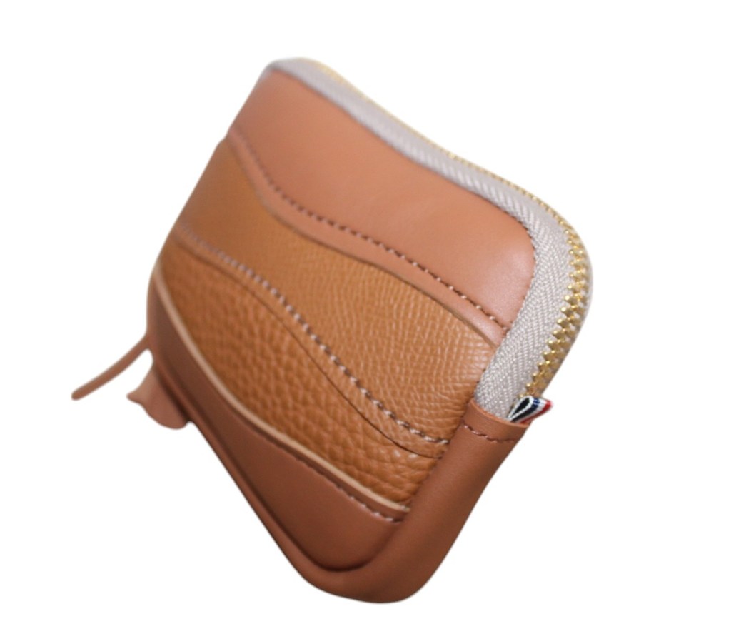 Le portemonnaie créateur fabriqué avec des cuirs lisses et grainés pleine fleur.